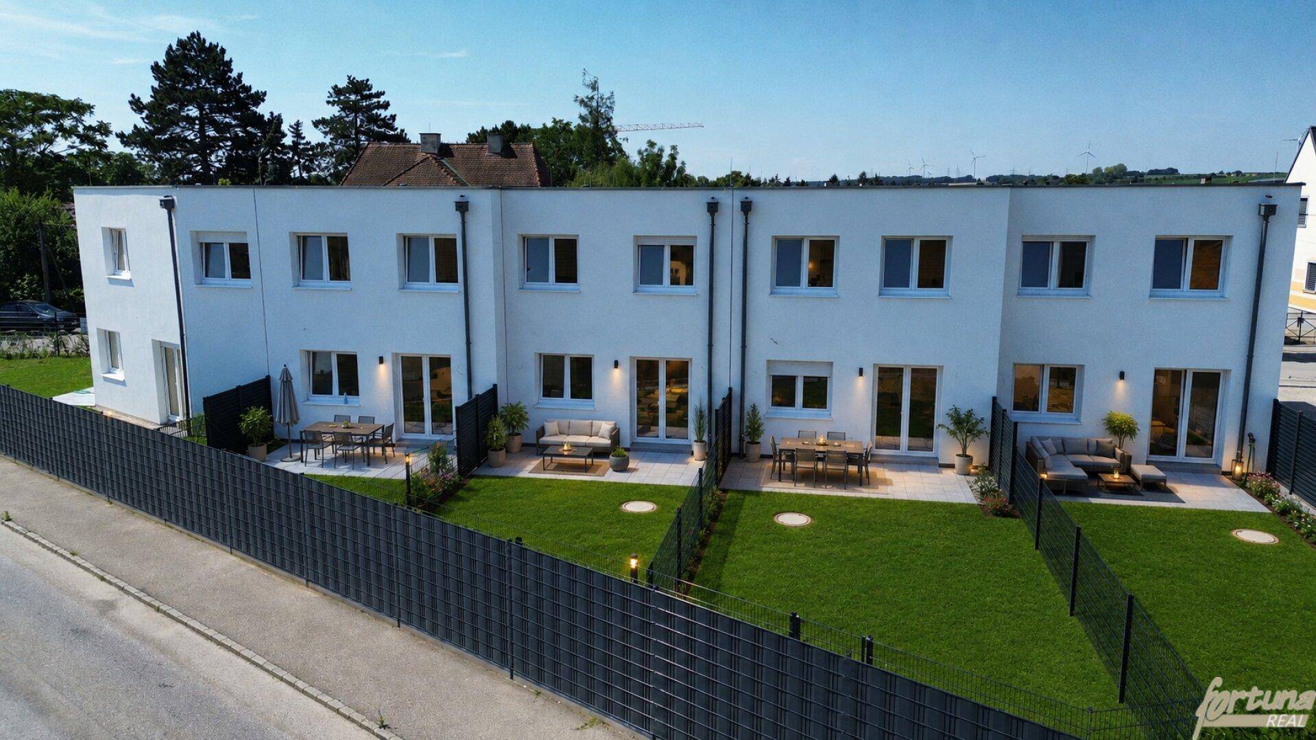 Moderne Reihenhäuser mit privaten Gärten und möblierten Terrassen, ideal für entspannte Stunden im Freien.