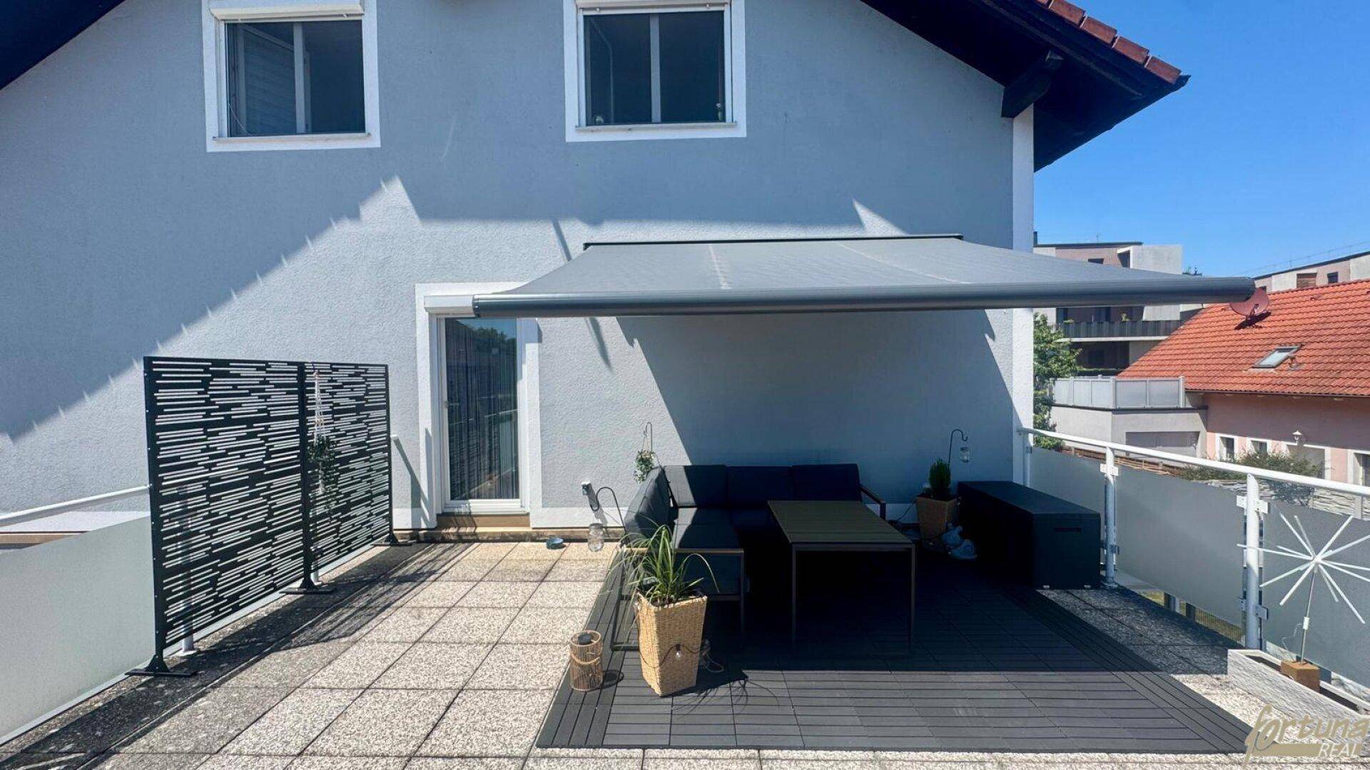 Geräumiger Balkon mit moderner Möblierung, Sonnenschutz und Blick auf die Umgebung.