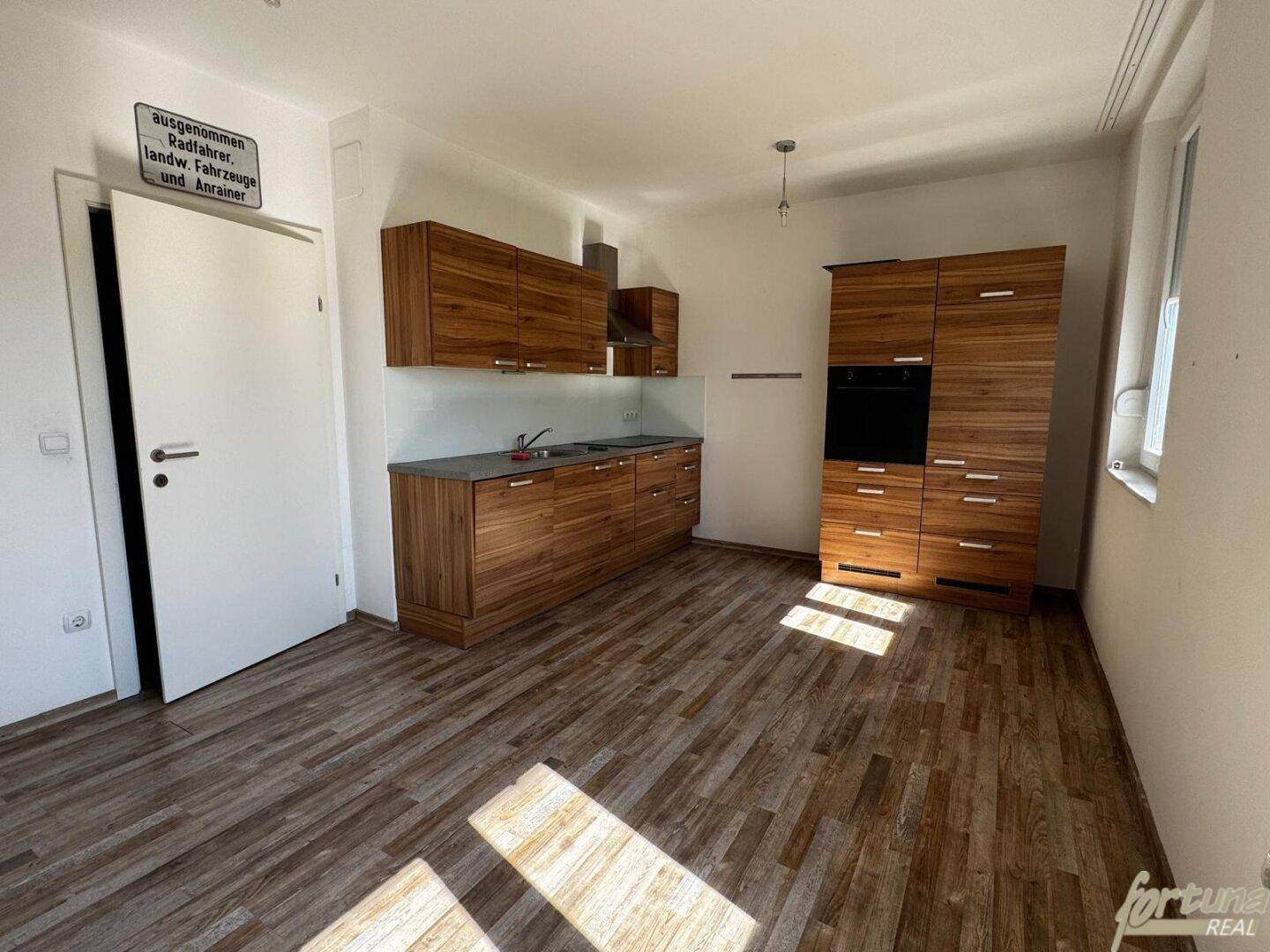 Moderne Küche mit Holzschränken, dunkler Arbeitsplatte und integrierten Geräten.