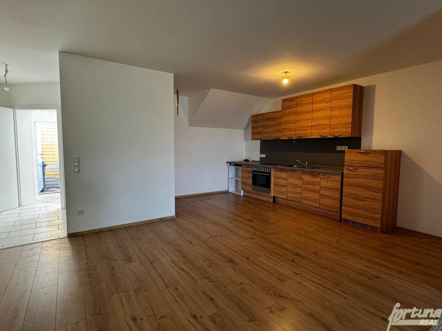 Offene Küche mit Holzschränken und dunkler Arbeitsplatte, integriert in einen Wohnbereich.