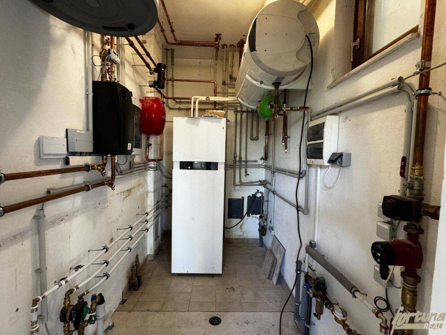 Heizungsraum mit Boiler und komplexer Rohrinstallation, gut organisiert.