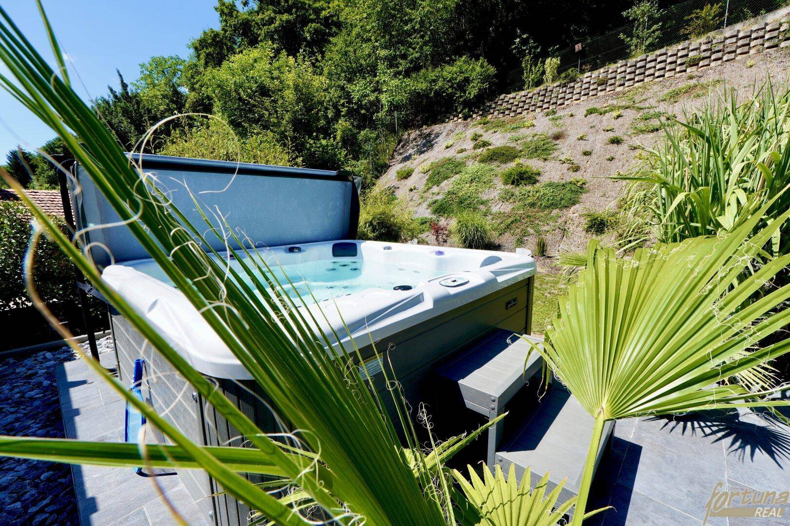 Moderner Whirlpool auf der Terrasse, umgeben von mediterranen Pflanzen.