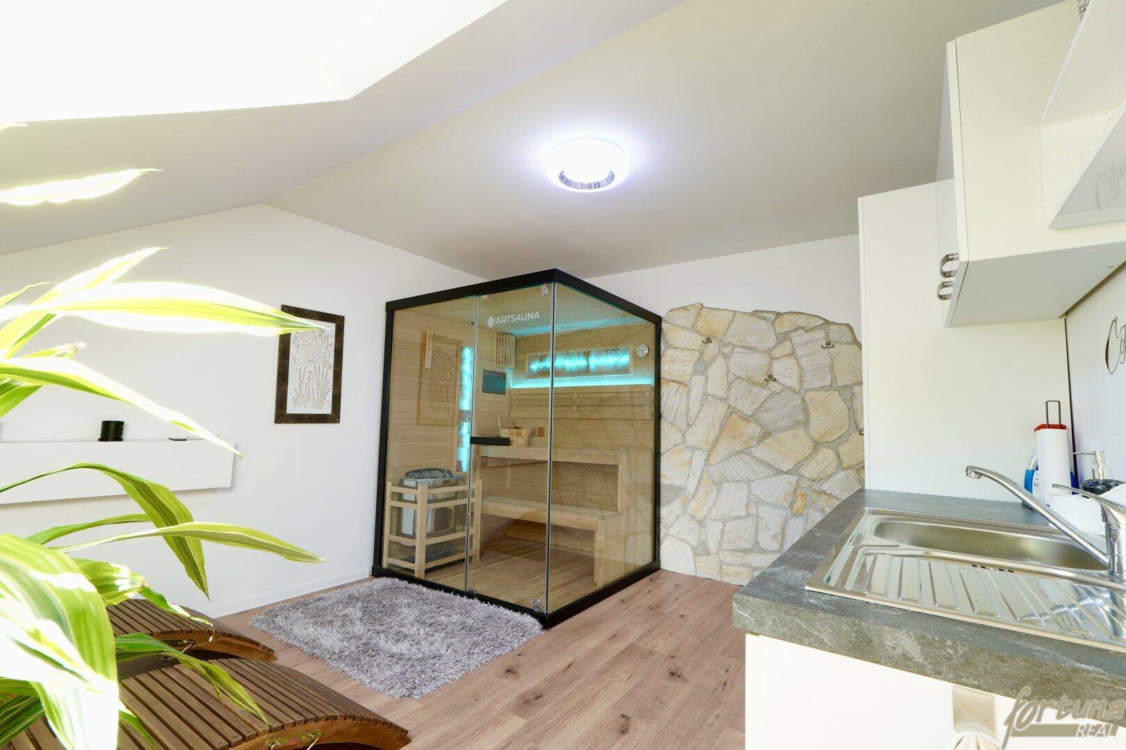 Entspannender Wellnessbereich mit moderner Sauna und kleiner Küchenzeile.