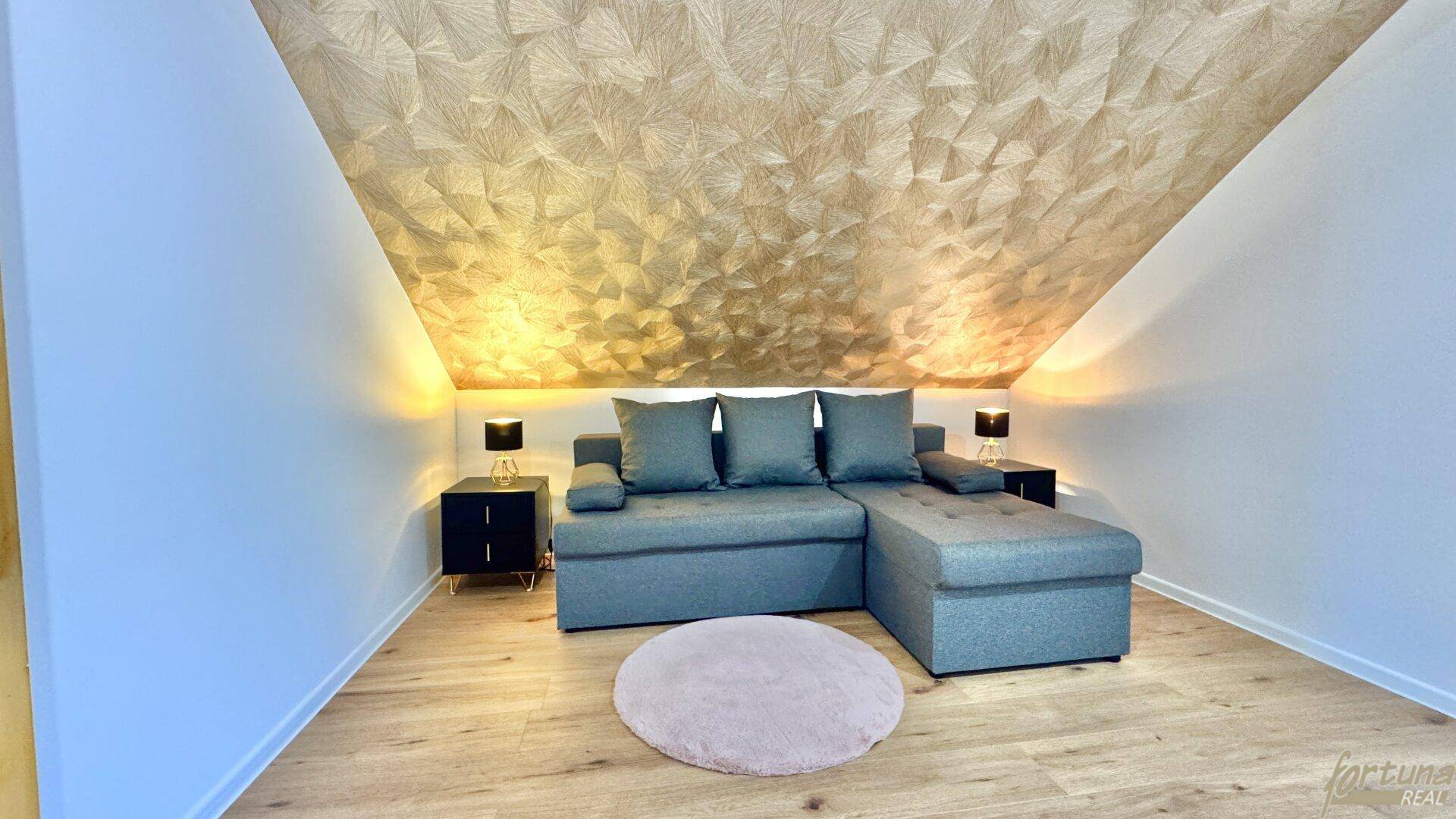 Gemütliches Zimmer mit Schlafcouch und dekorativer Deckenverkleidung.