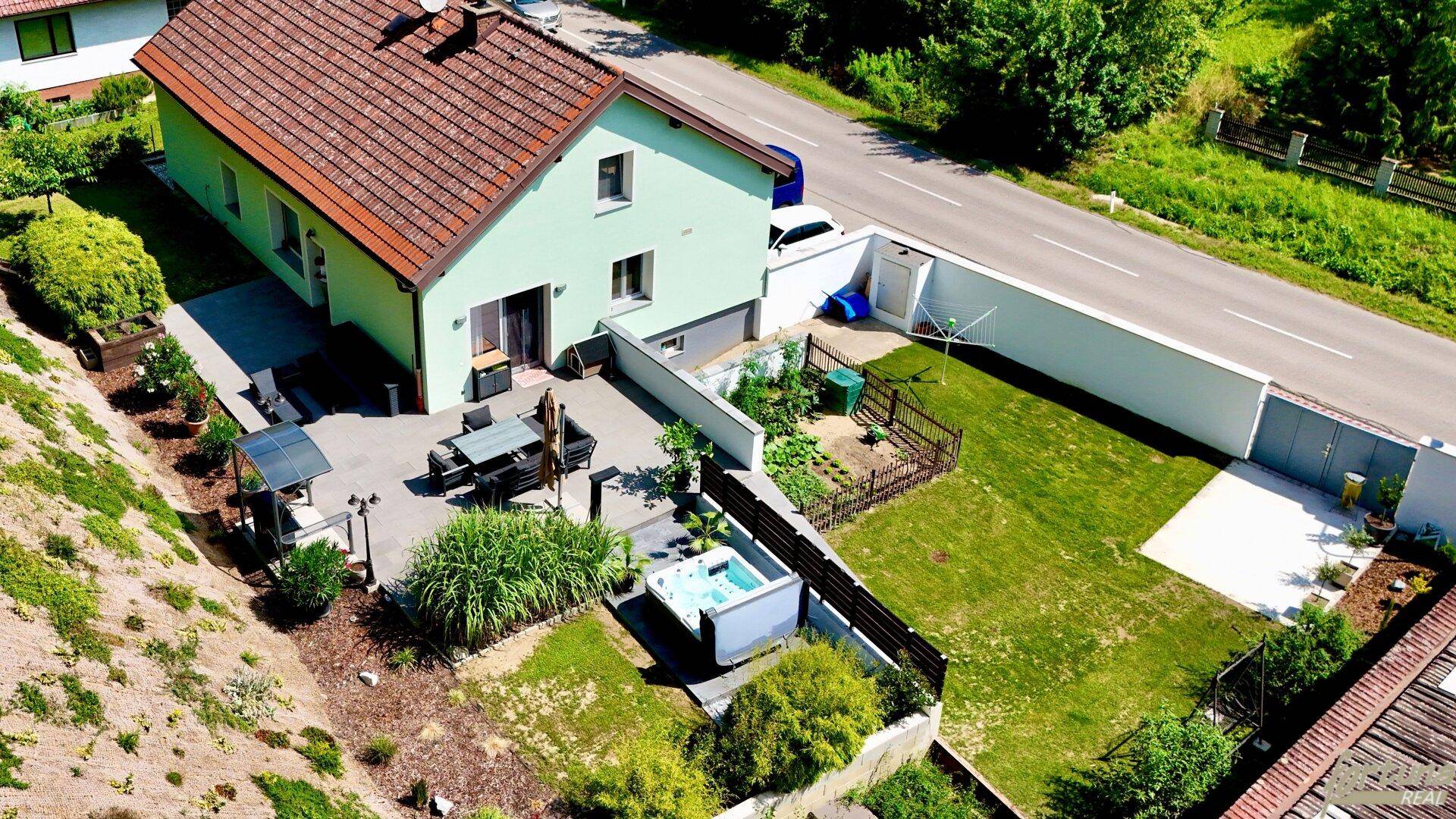 Luftaufnahme eines Einfamilienhauses mit Garten, Terrasse und Whirlpool.