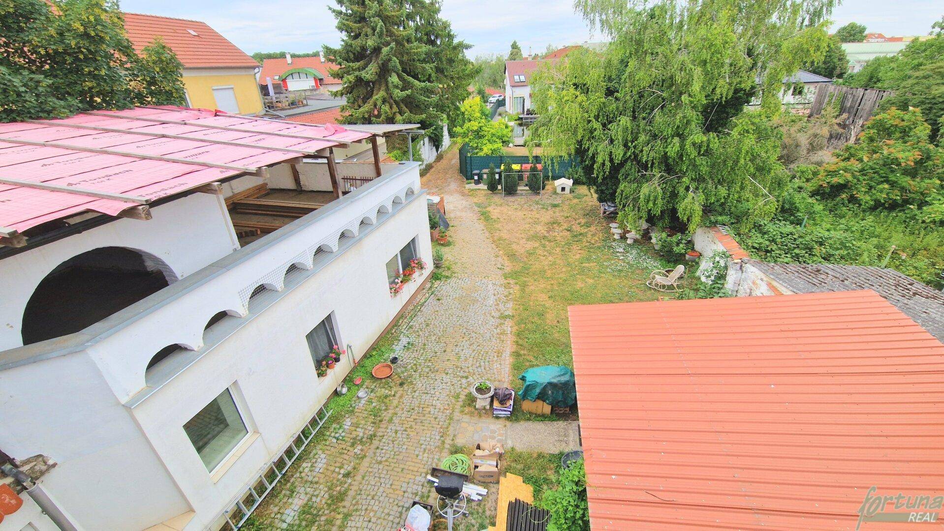 Luftaufnahme des Anwesens mit Gebäude, Innenhof und dem weitläufigen Gartenbereich.