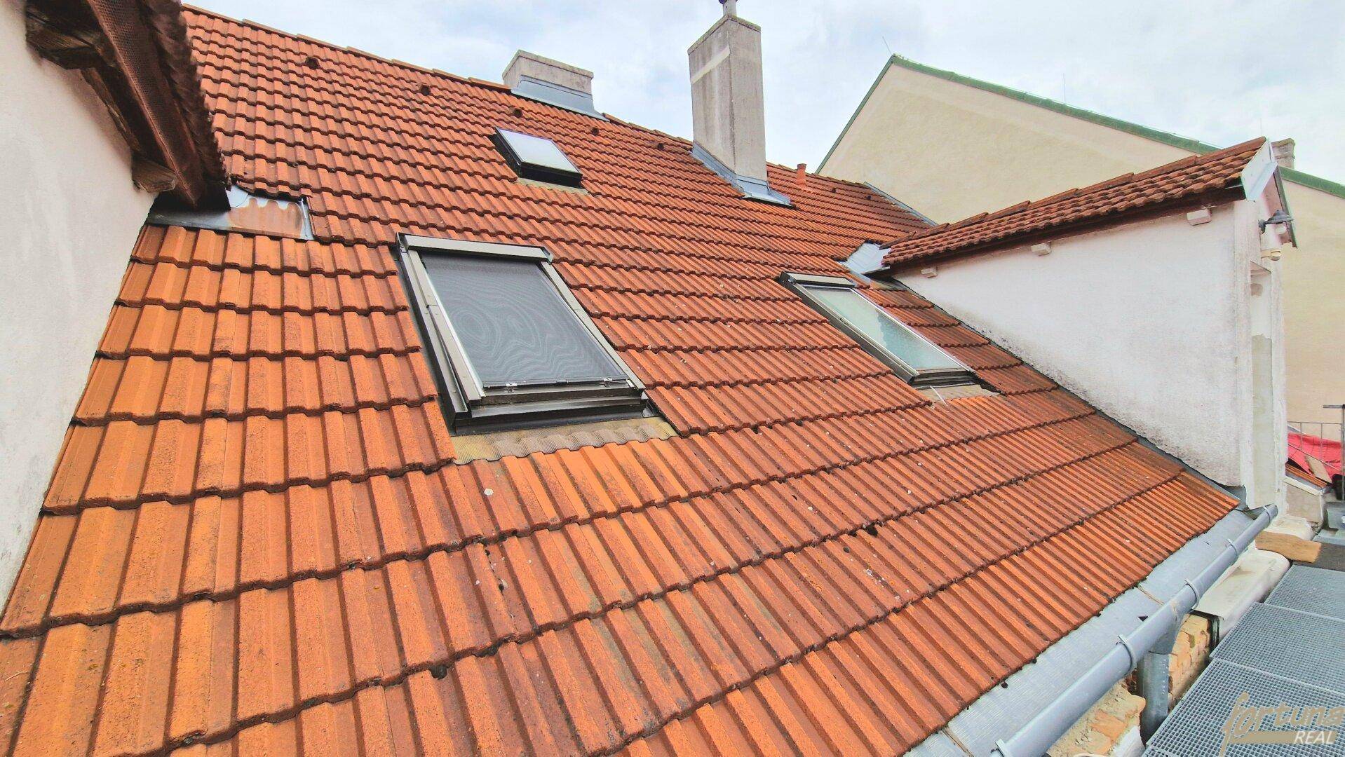 Dachfläche mit roten Ziegeln und mehreren Dachfenstern, die Licht in die oberen Etagen bringen.
