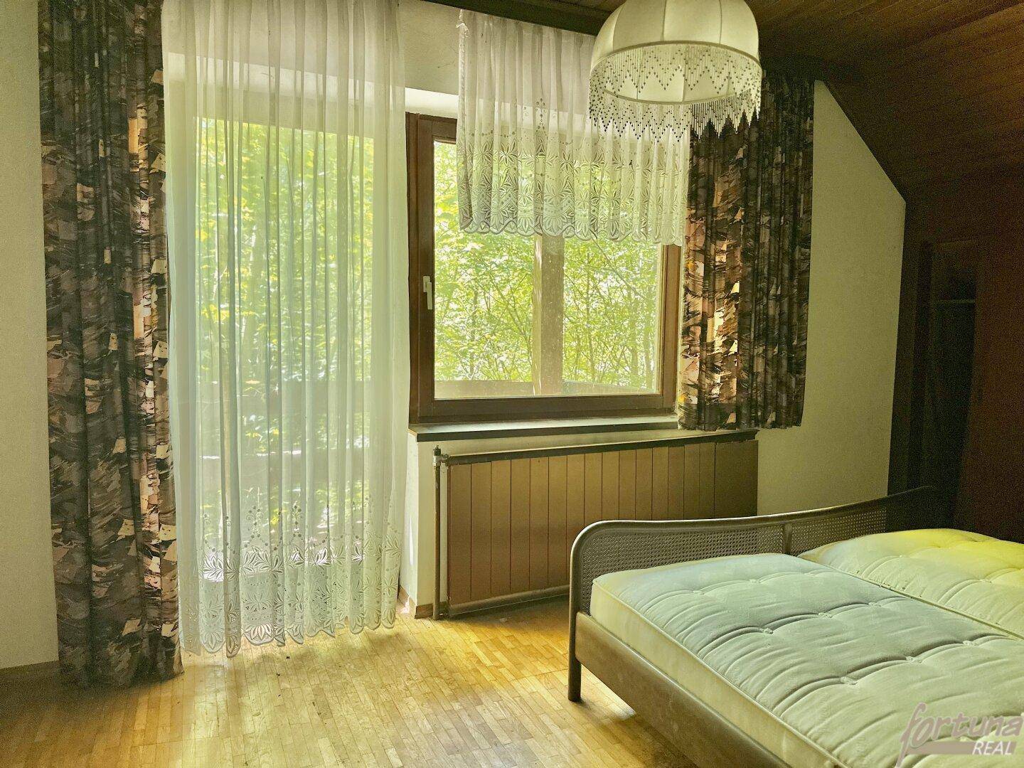 Helles Schlafzimmer mit Holzboden, großen Fenstern und einem Bett im traditionellen Stil.