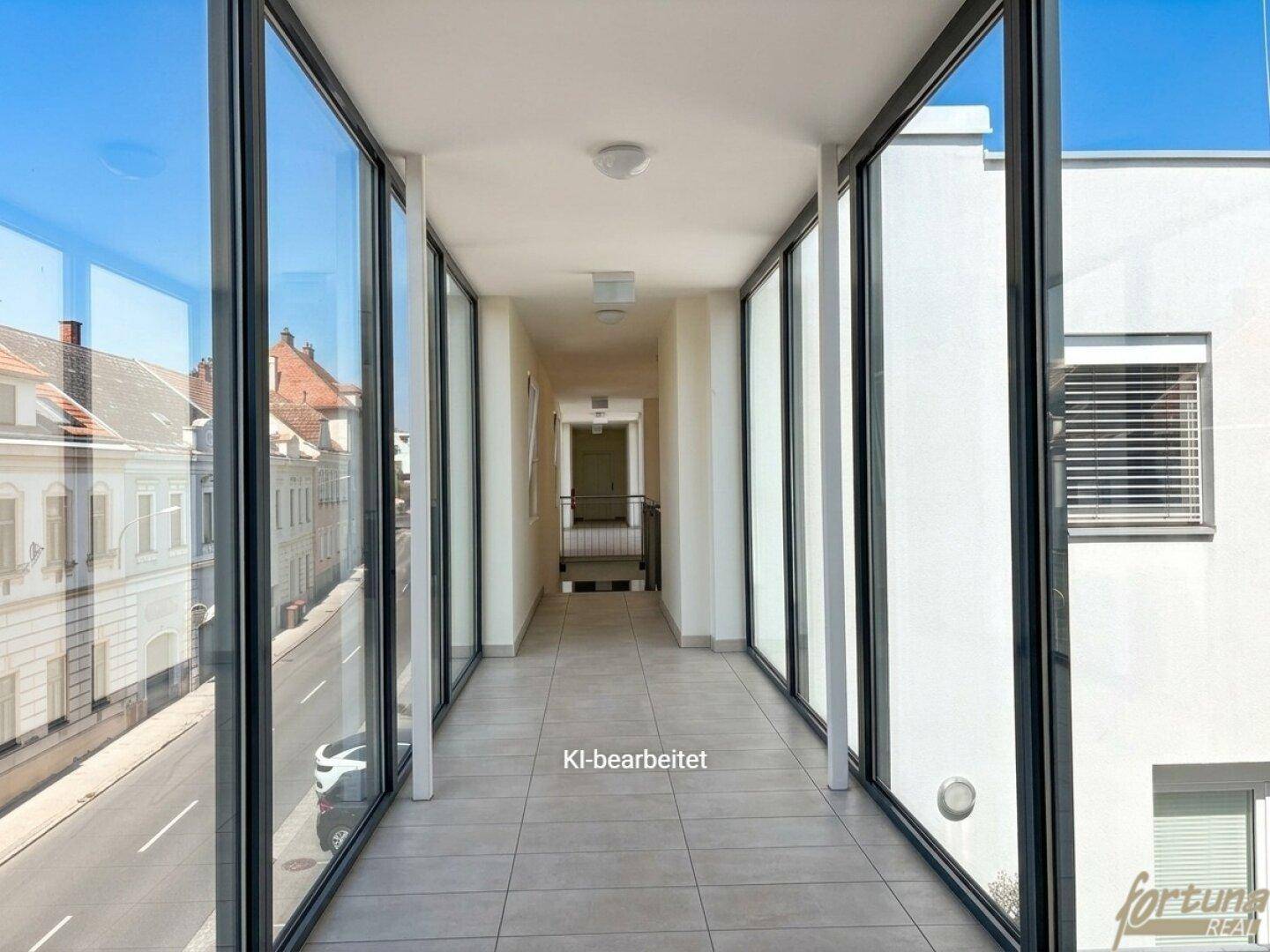 Heller Flur mit großen Glasfronten und Fliesenboden, bietet einen Blick auf die Straße.