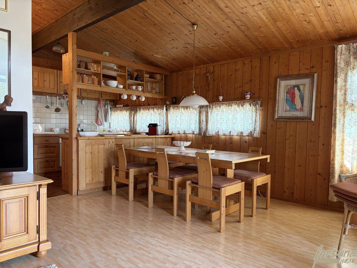 Rustikale offene Küche mit Holzeinbauten und Essbereich unter Holzdachschrägen.