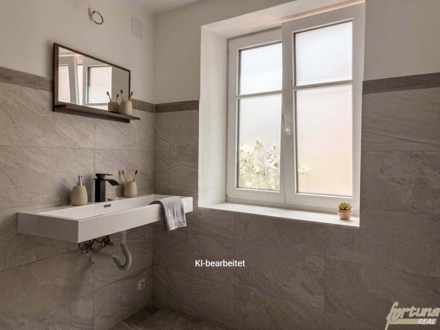Modernes Badezimmer mit grauen Fliesen, wandhängendem Waschbecken und Fenster für Tageslicht.