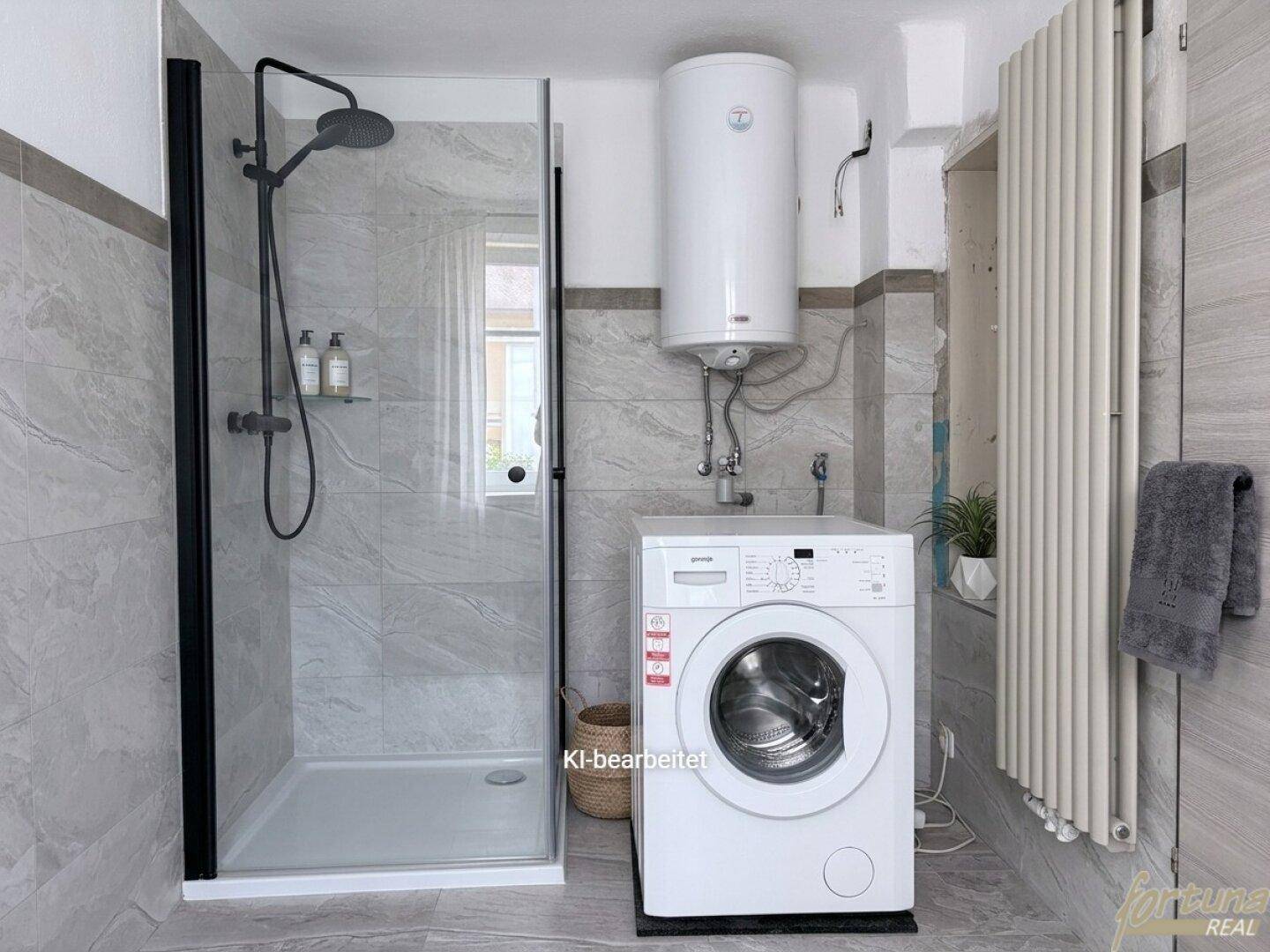 Badezimmer mit Duschkabine, Waschmaschine und Heizkörper, komplett gefliest.