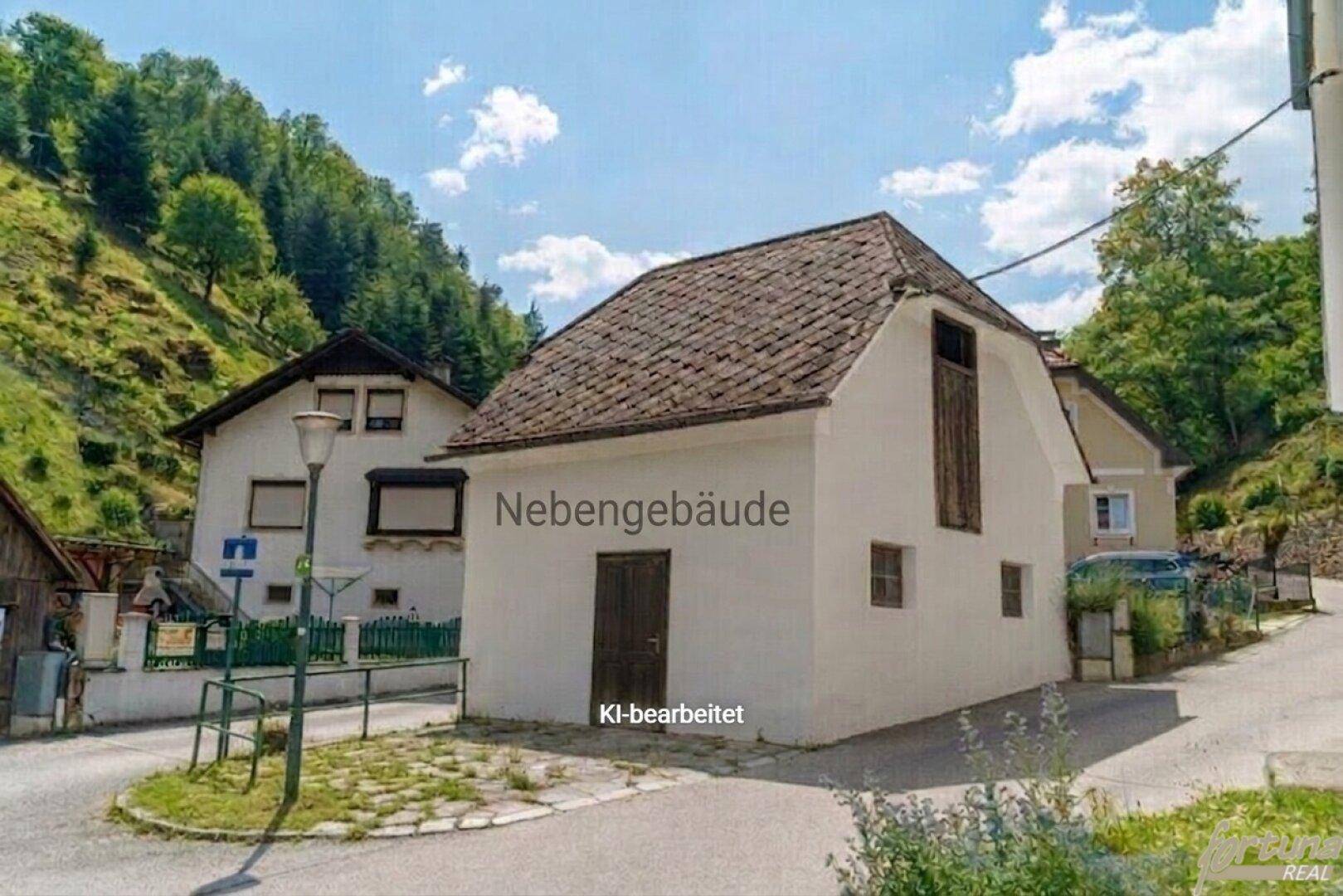 Außenansicht eines kleinen Nebengebäudes mit Satteldach neben dem Haupthaus.