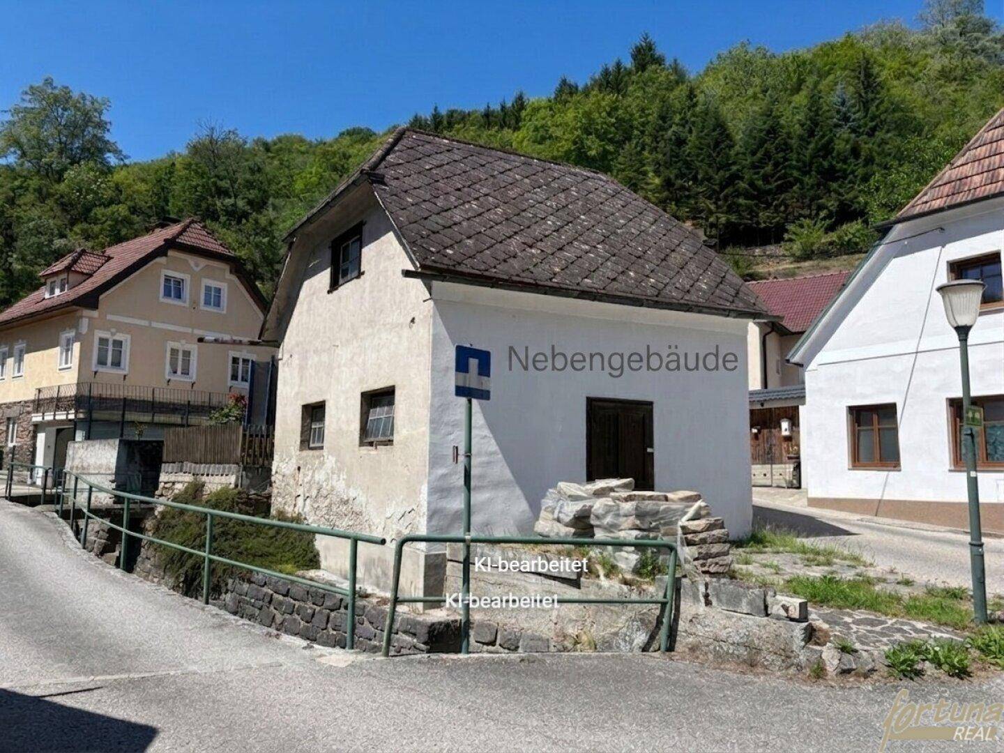 Außenansicht eines weiteren Nebengebäudes mit Satteldach an einer abschüssigen Straße.