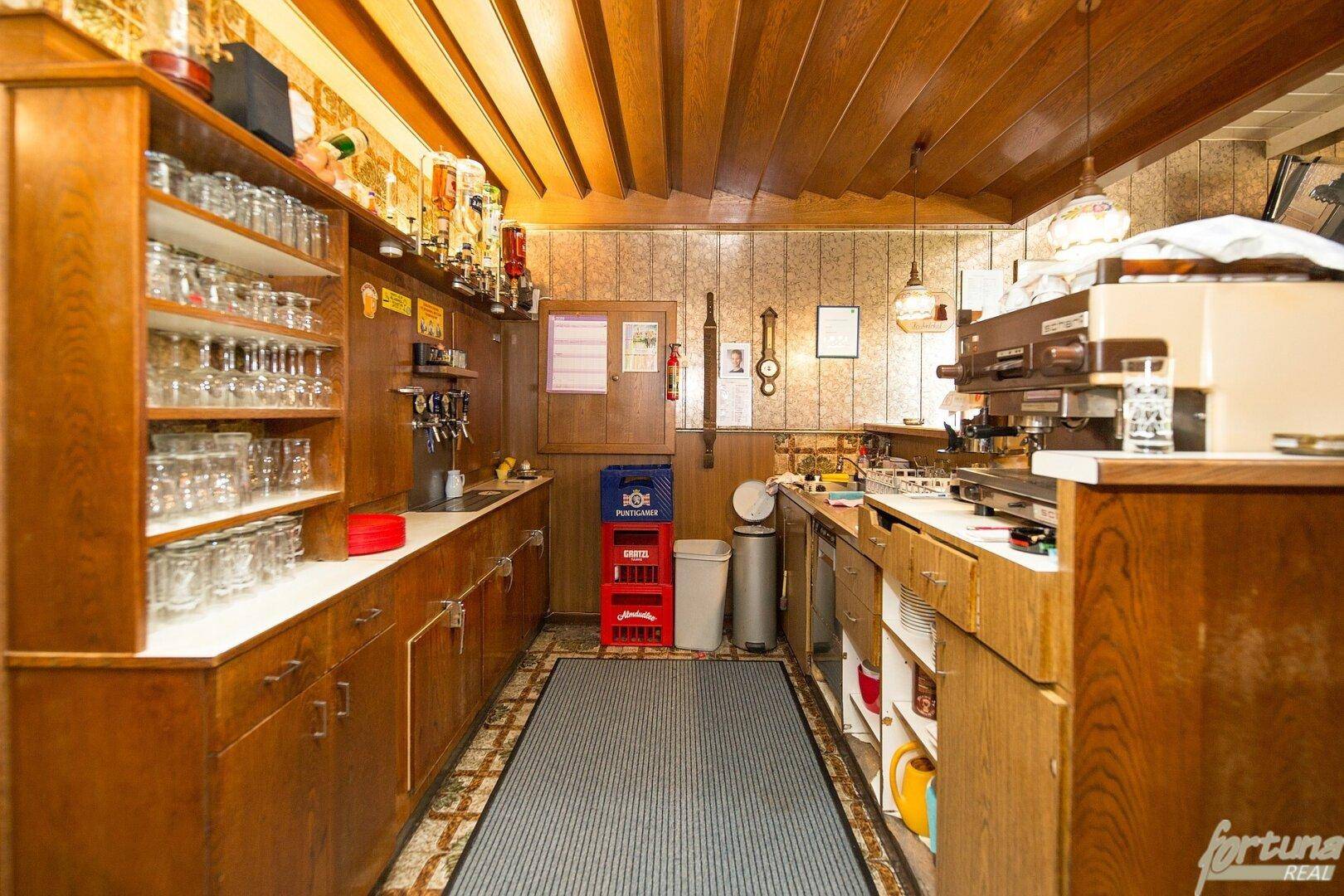 Ausgestattete Bar mit Holzverkleidung, Regalen für Gläser und Kaffeemaschine.