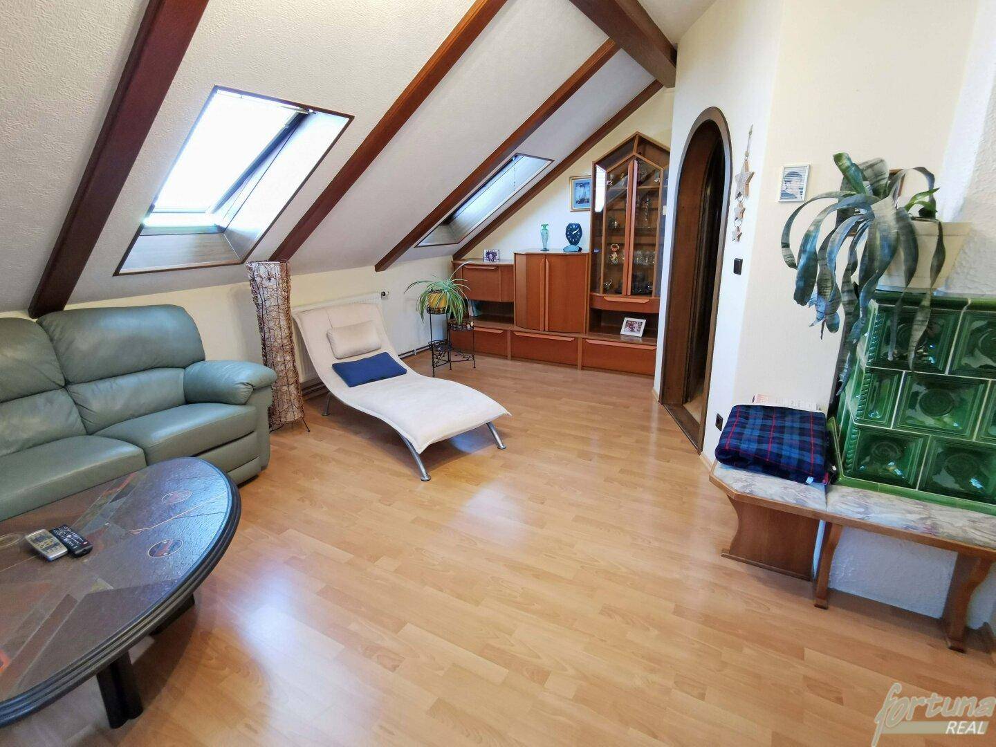Gemütliches Dachgeschoss-Wohnzimmer mit Holzboden, Kachelofen und Dachfenstern.
