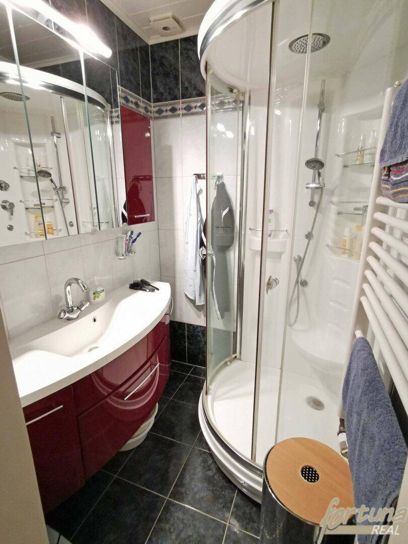 Modernes Badezimmer mit Duschkabine, Waschbecken und beheiztem Handtuchhalter.