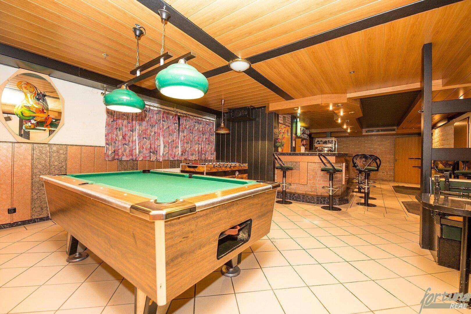 Geräumiger Spielraum mit Billardtisch und Barbereich, ideal für Unterhaltung.