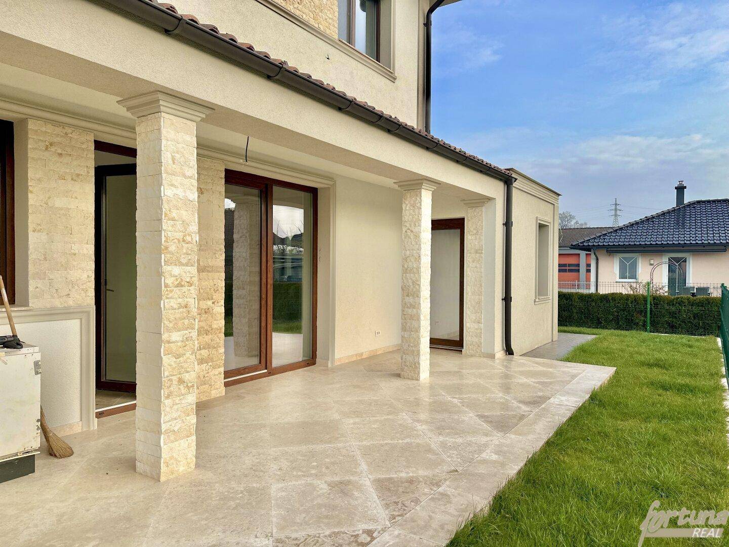 Geräumige, geflieste Terrasse mit Säulen und direktem Zugang zum Gartenbereich der Doppelhaushälfte.