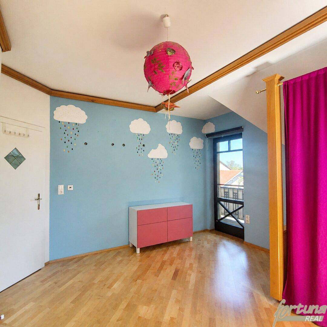 Kinderzimmer mit verspielter Wandgestaltung, Holzbalken und Zugang zu einem kleinen Balkon.