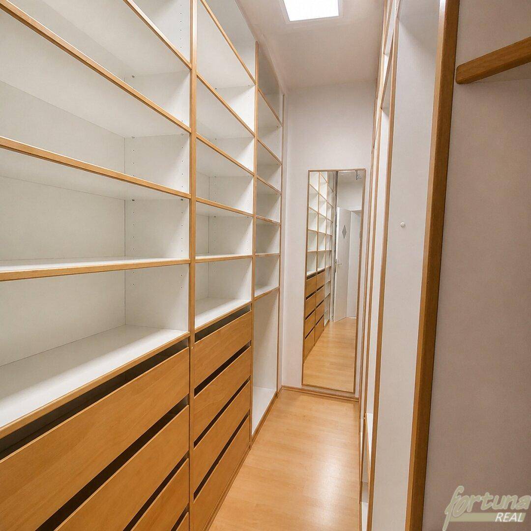 Praktischer begehbarer Kleiderschrank mit vielen Regalen und Schubladen sowie einem Spiegel.