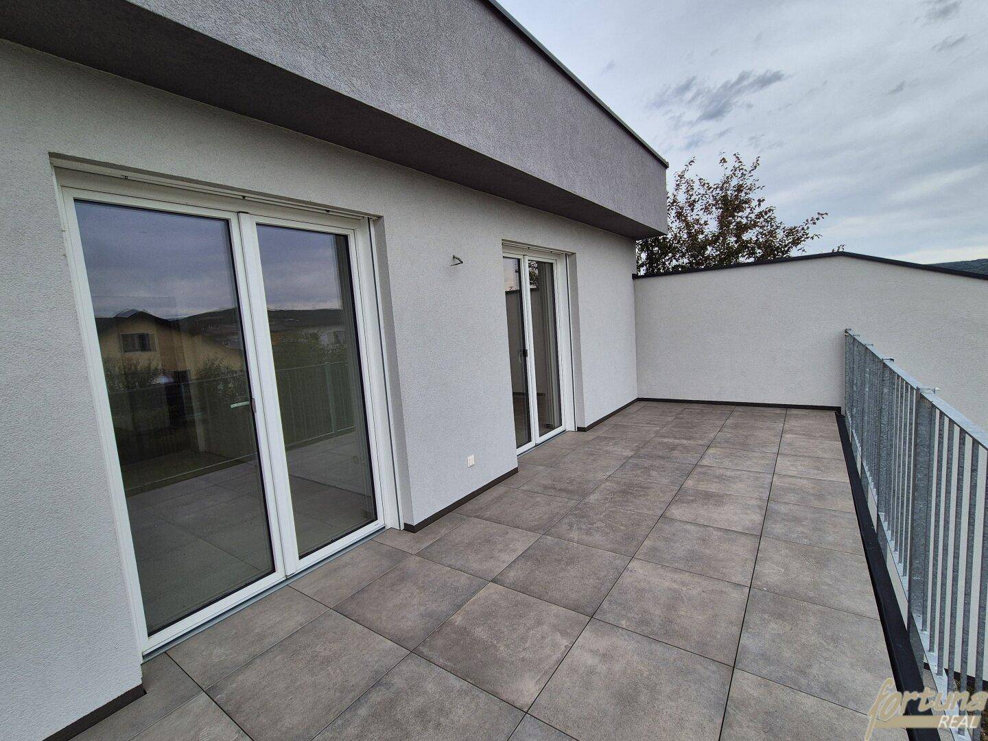 Geräumige Dachterrasse mit modernen grauen Fliesen und stabilem Metallgeländer.