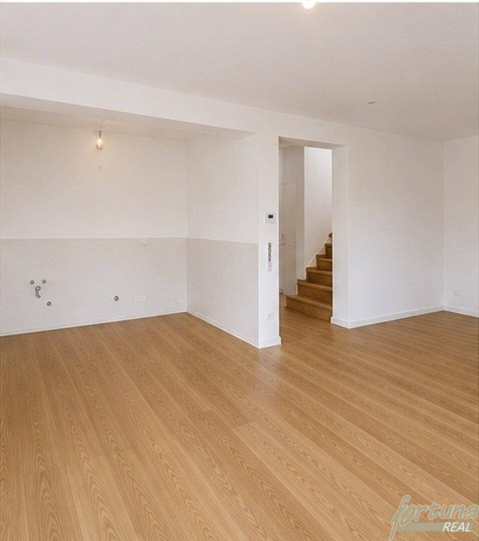 Offener Wohnbereich mit Holzfußboden und Blick auf die moderne Holztreppe.