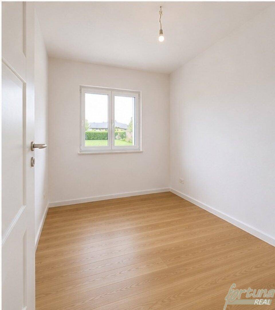 Helles Schlafzimmer mit Holzfußboden, weißen Wänden und einem großen Fenster.