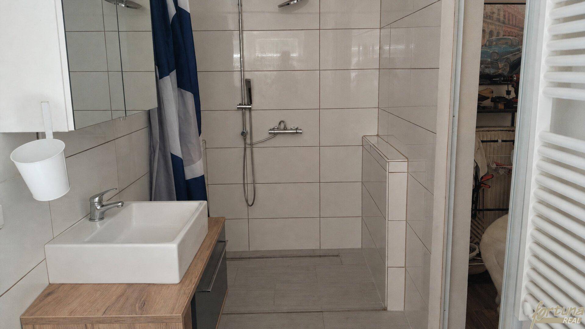 Helles Badezimmer mit ebenerdiger Dusche, modernem Waschbecken und weißen Wandfliesen.