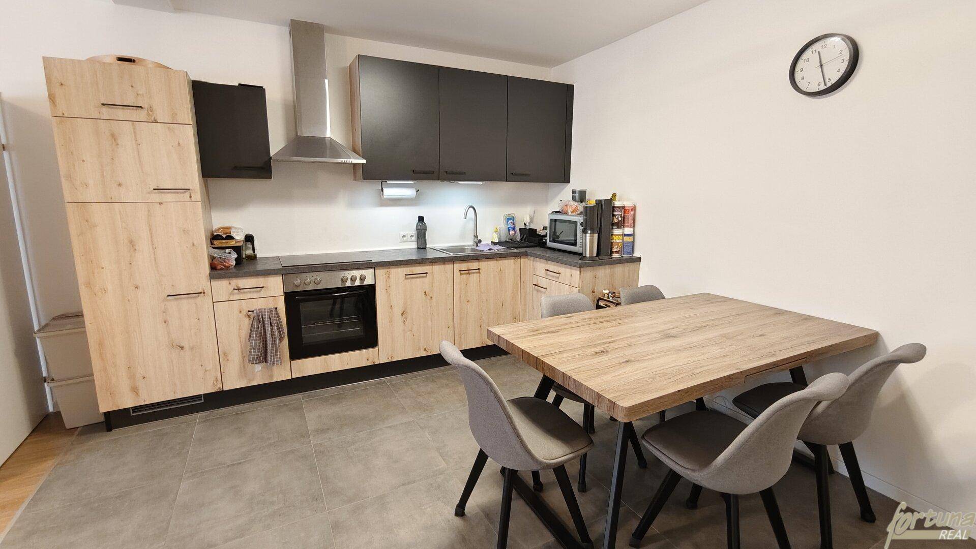 Moderne Einbauküche mit Holz- und Anthrazitfronten, integriertem Backofen und Essbereich für die Familie.