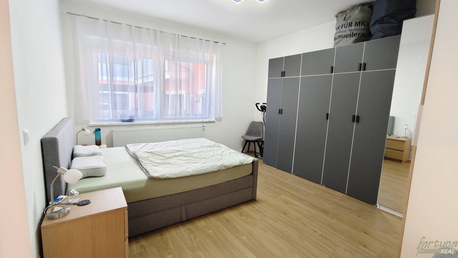 Schlafzimmer mit großem Doppelbett, geräumigem Kleiderschrank und hellem Laminatboden für Komfort.