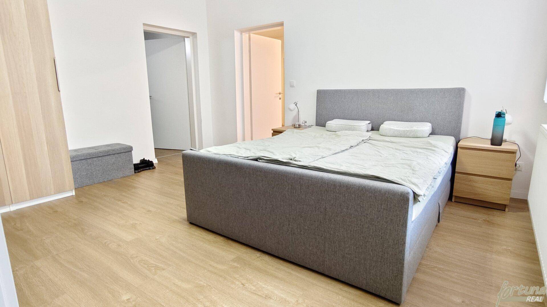Geräumiges Schlafzimmer mit bequemen Bett und Zugang zu weiteren Räumen, bietet viel Platz.