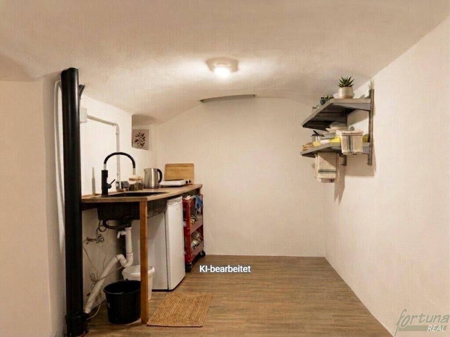 Kleine, funktionale Küche mit Holztheke, Spülbecken und Laminatboden in einem einfachen Raum.