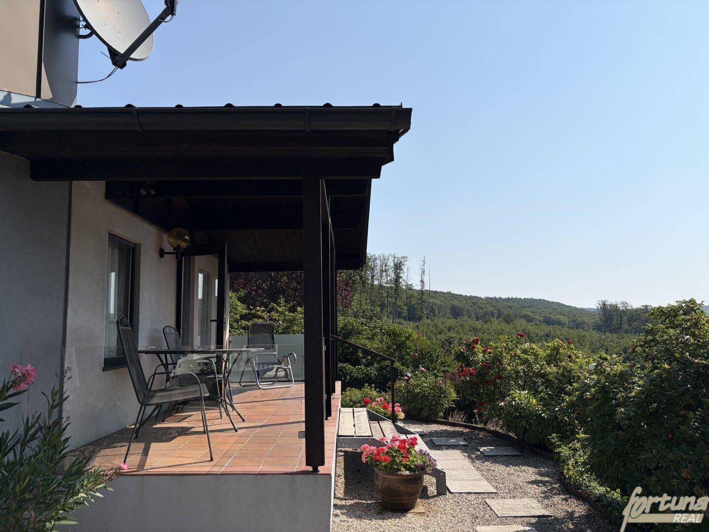 Gemütliche Fliesenterrasse mit Gartenmöbeln und Blick auf die umliegende Natur.