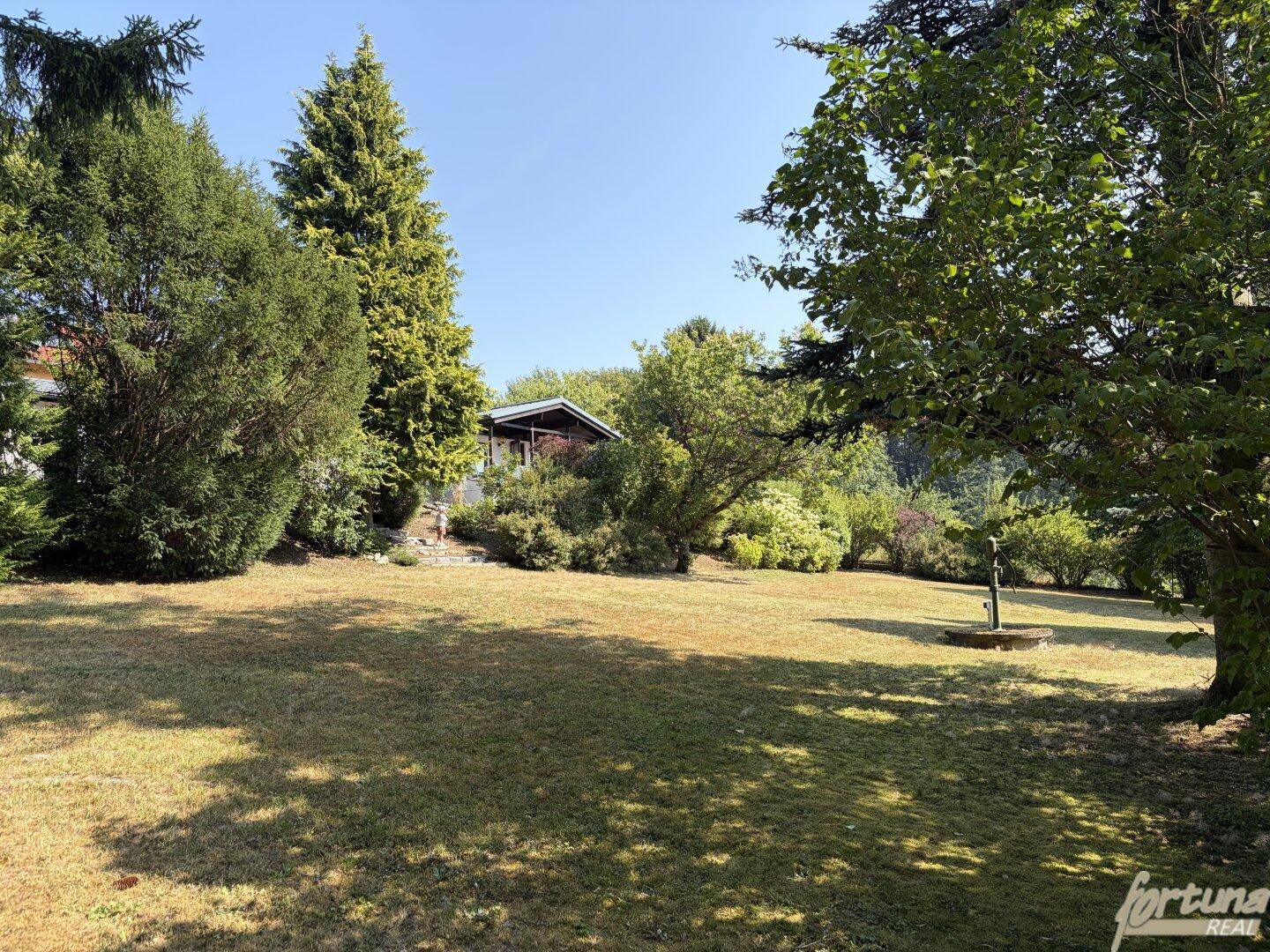 Großer, gepflegter Garten mit Rasenfläche, altem Baumbestand und einem kleinen Gartenhaus.