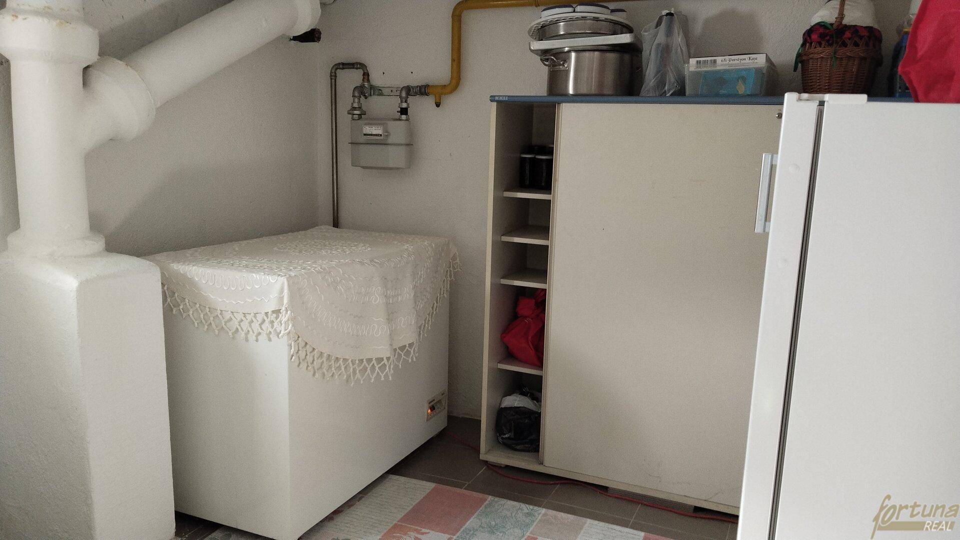 Kellerbereich mit Gefriertruhe, Schrank und Versorgungsleitungen, dient als zusätzlicher Abstellraum.