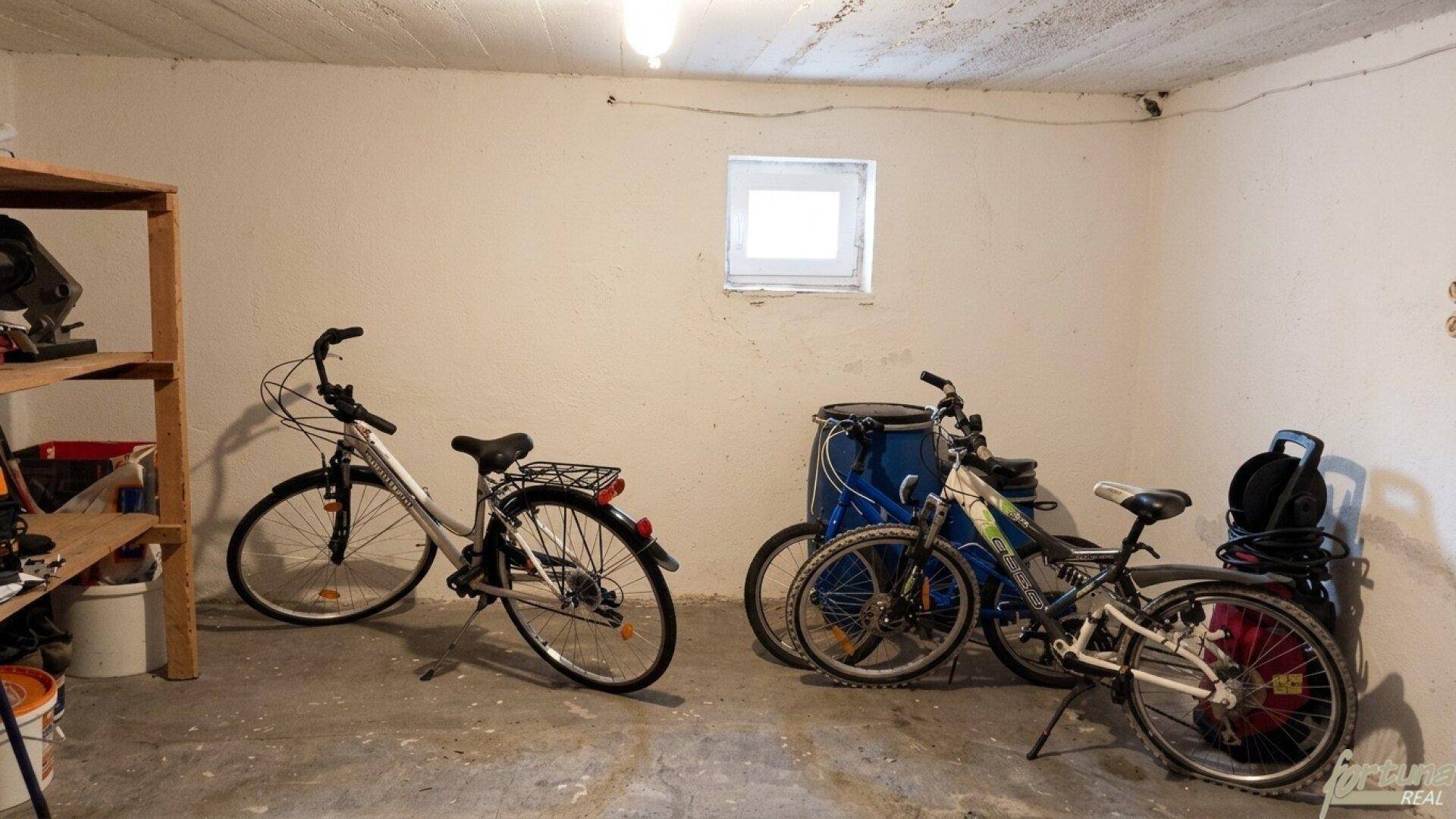 Kellerraum mit Fahrrädern und Regalen, bietet praktischen Stauraum und ein kleines Fenster.