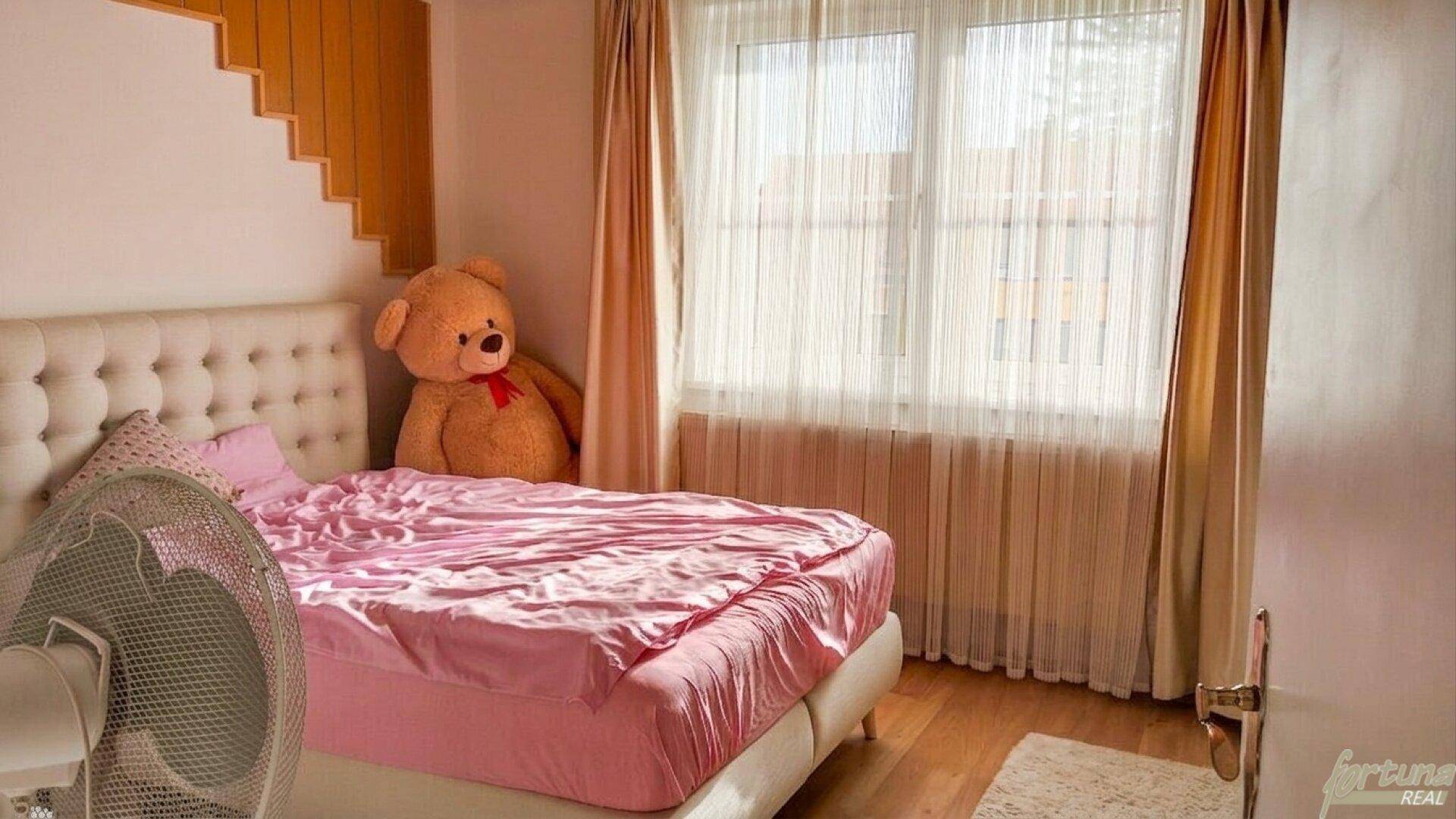 Gemütliches Schlafzimmer mit großem Bett, rosa Bettwäsche und hellem Holzboden.