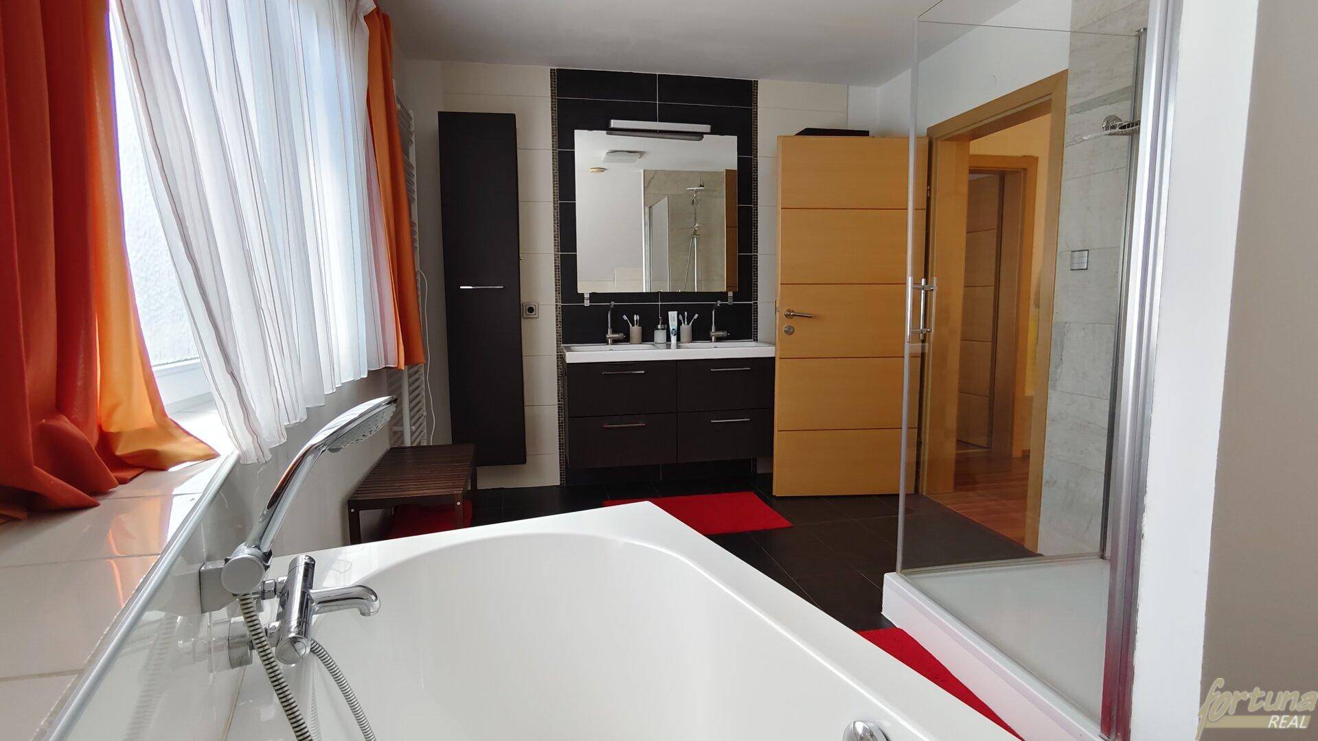 Modernes Badezimmer mit Badewanne, separater Dusche und dunklem Waschtischunterschrank.