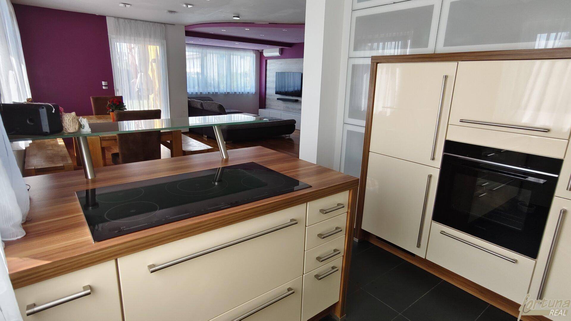 Moderne Einbauküche mit Induktionskochfeld, Backofen und hellen Schränken.