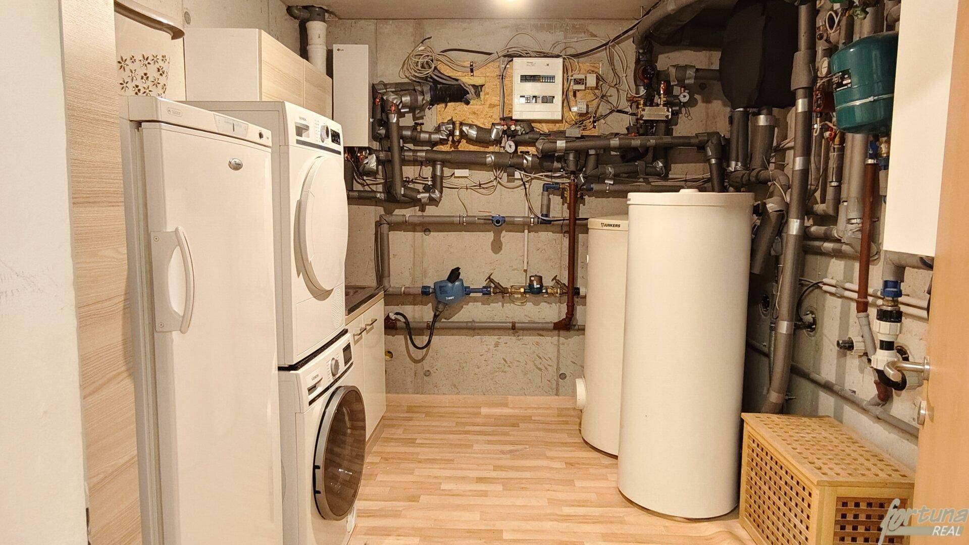 Funktionaler Hauswirtschaftsraum mit Waschmaschine, Trockner und Heizungsanlage im Keller.