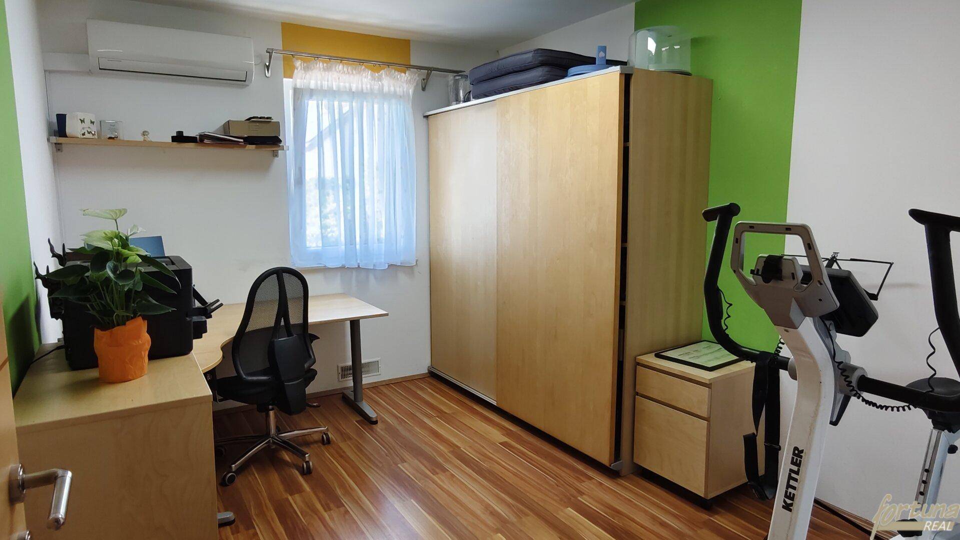 Vielseitiger Raum als Büro und Fitnessbereich mit Holzboden und Schiebetürenschrank.