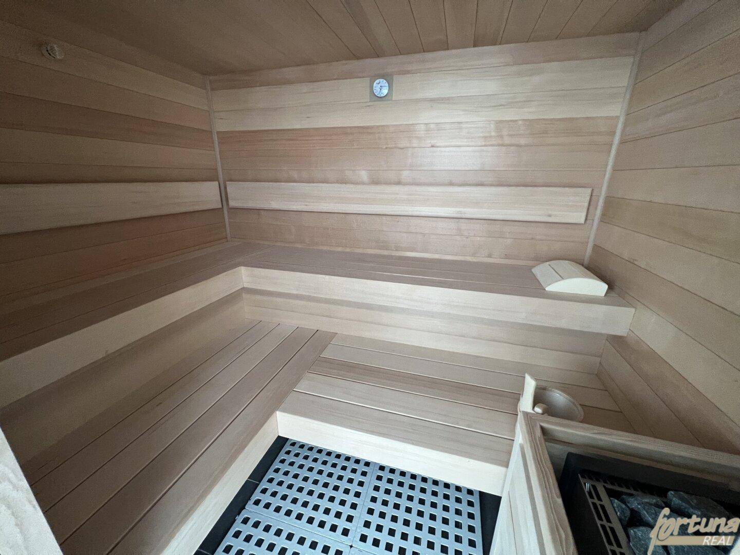 Innenansicht der modernen Holzsauna mit Bänken und Saunaofen für Entspannung.