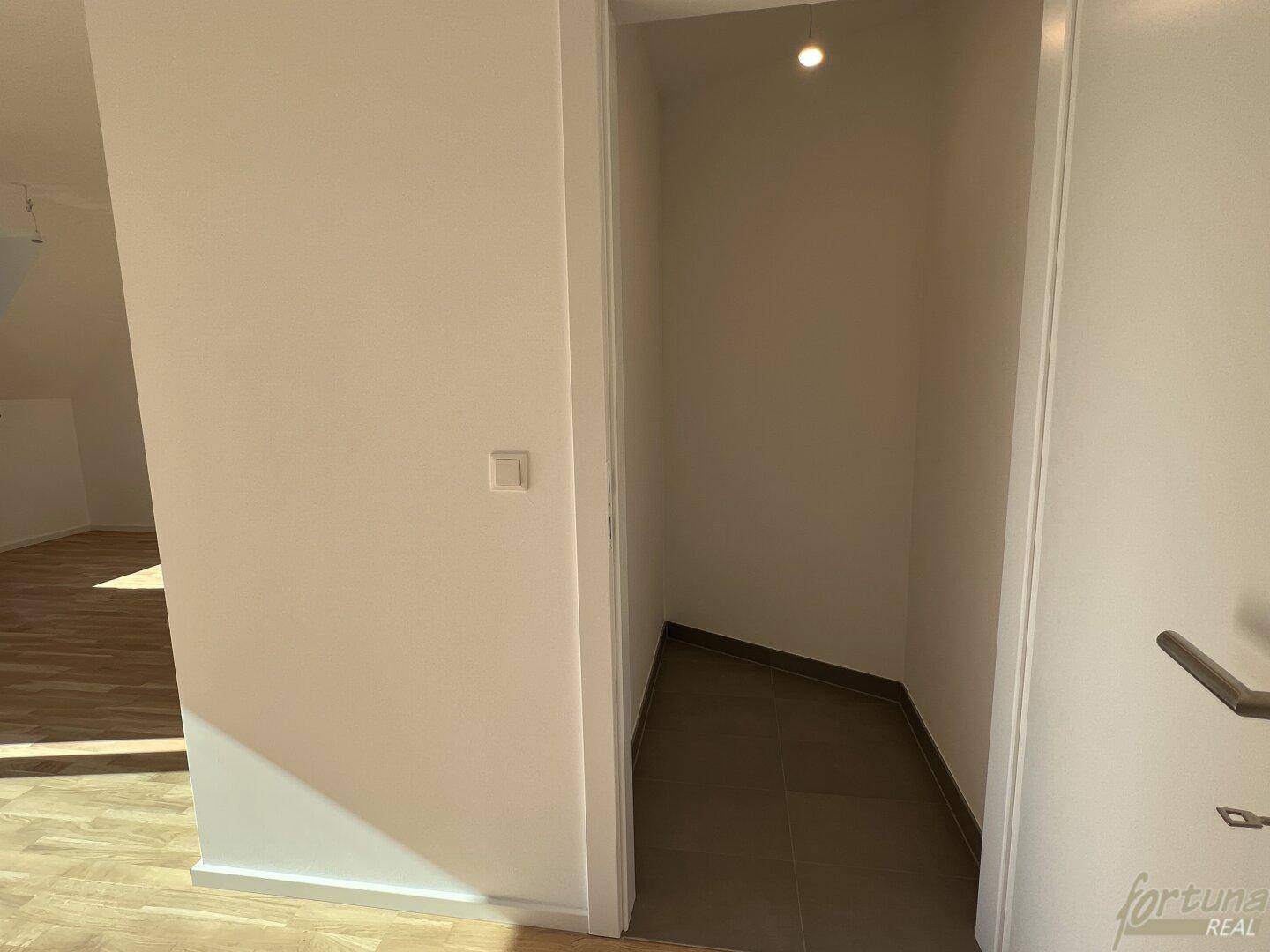 Praktischer Abstellraum oder Nische im Flur mit Fliesenboden und Dachschräge.