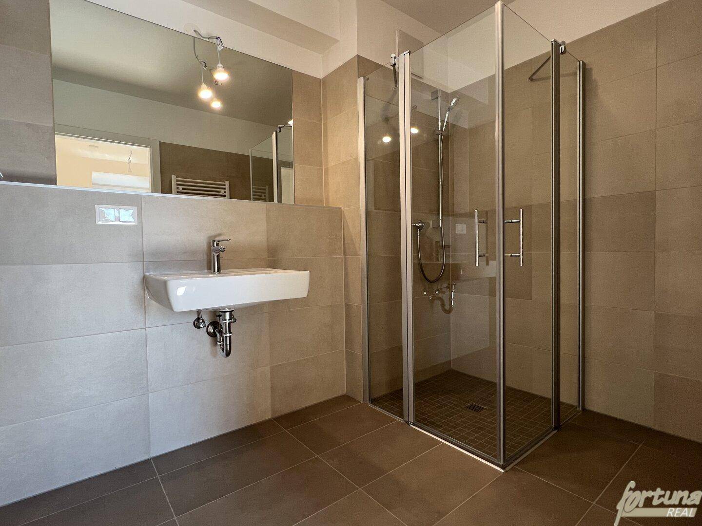 Modernes Badezimmer mit begehbarer Dusche, großformatigen Fliesen und Einzelwaschbecken.