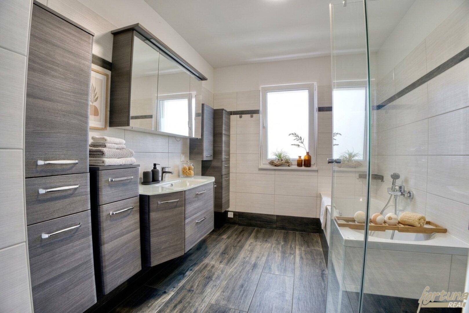 Modernes Badezimmer mit Doppelwaschbecken, Badewanne und separater Duschkabine.