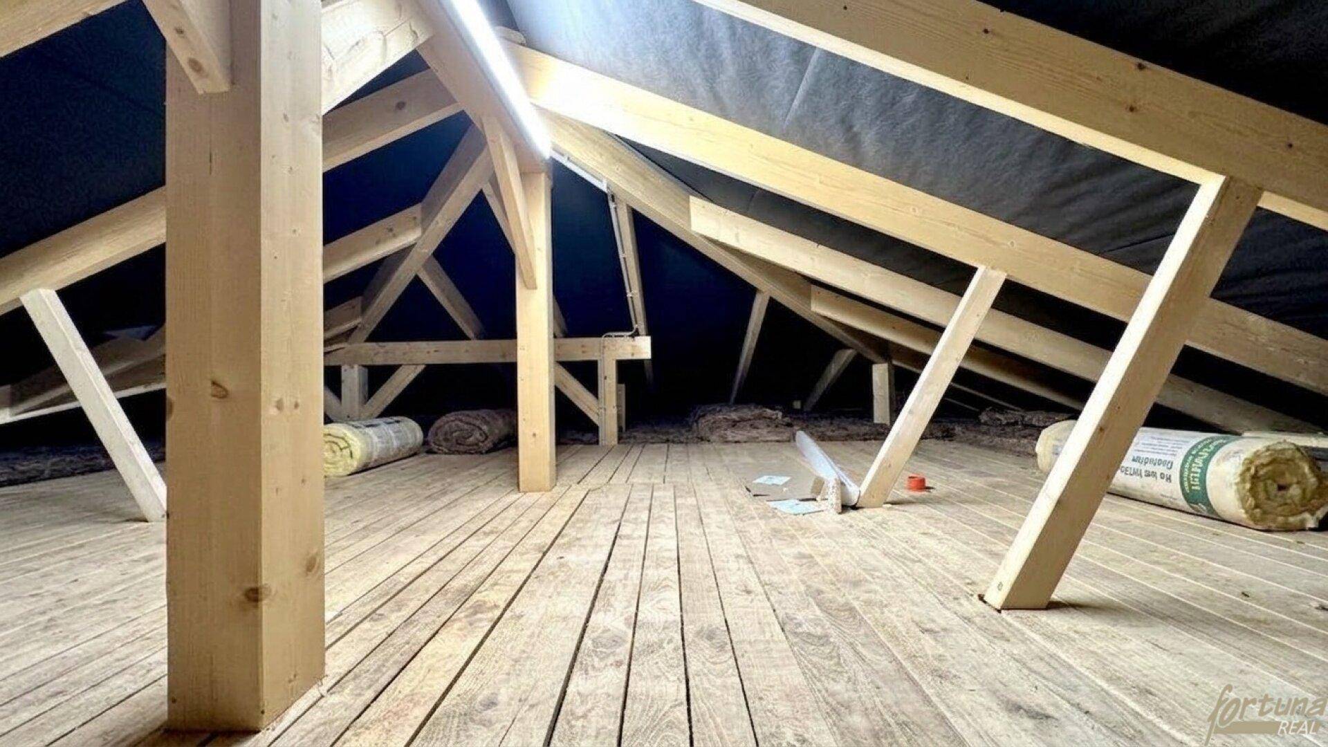 Unausgebauter Dachboden mit sichtbarer Holzkonstruktion und Dämmmaterial, bietet Ausbaupotenzial.