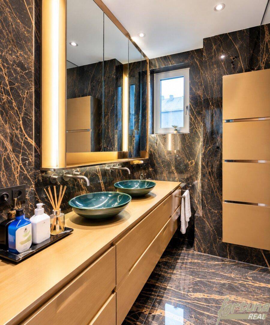 Luxuriöses Badezimmer mit dunklen Marmorfliesen, Doppelwaschbecken und beleuchtetem Spiegelschrank.