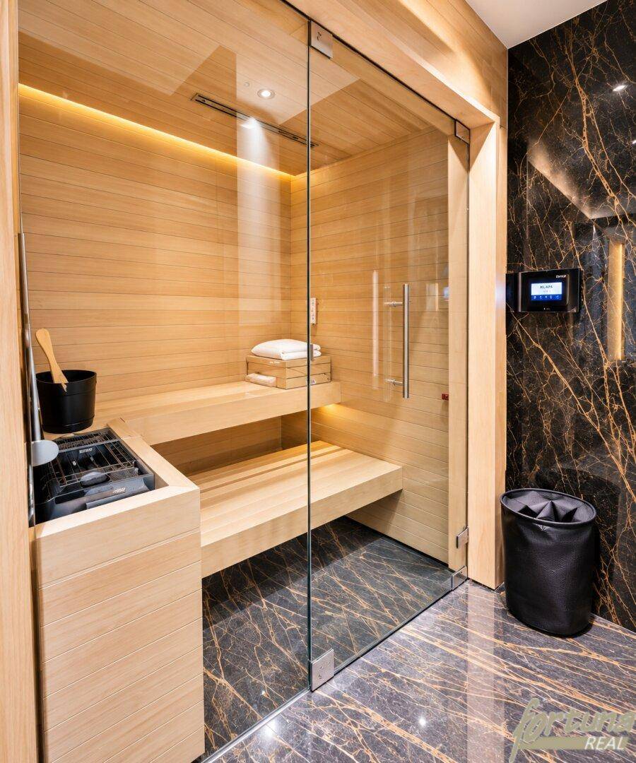 Private Sauna mit Holzbänken und Glasfront, integriert in ein luxuriöses Badezimmer.