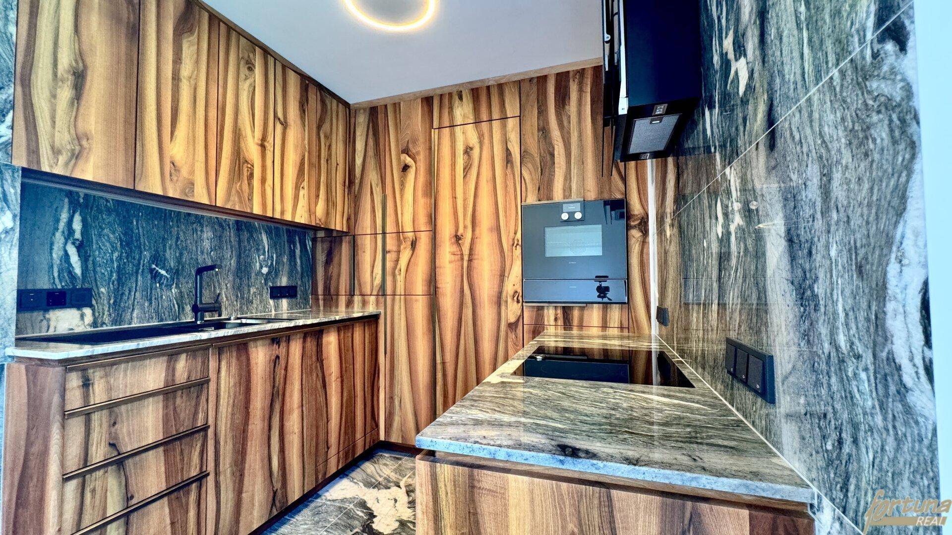 Hochwertige Küche mit Holzfronten, dunklen Marmorarbeitsplatten und modernen Einbaugeräten.